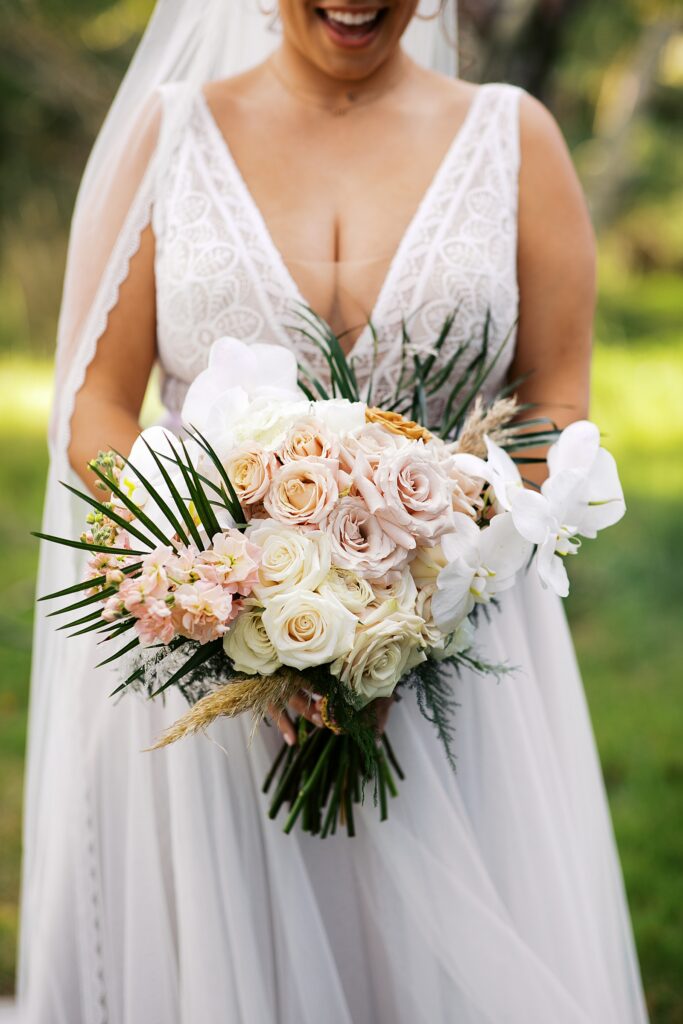 A bridal bouquet full of roses and orchids for a boho beach wedding.
