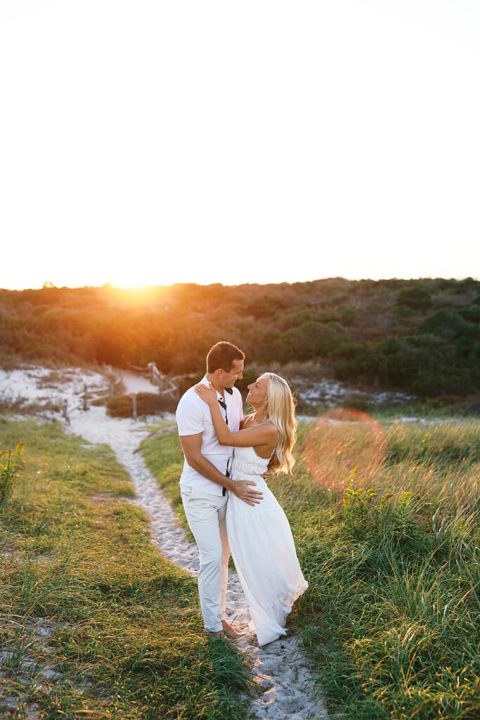 An engaged couple embraces one another on a small beach path in Island Beach State Park.