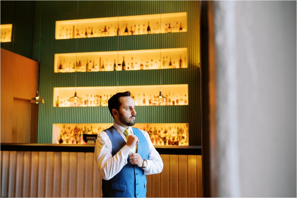 A groom poses in front of the bar in the Asbury Hotel lobby