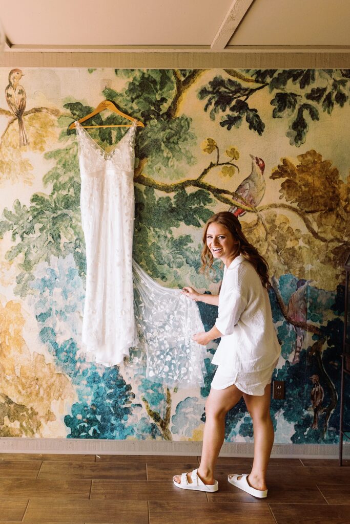 A bride holding her wedding dress in the mural room at Promise Ridge