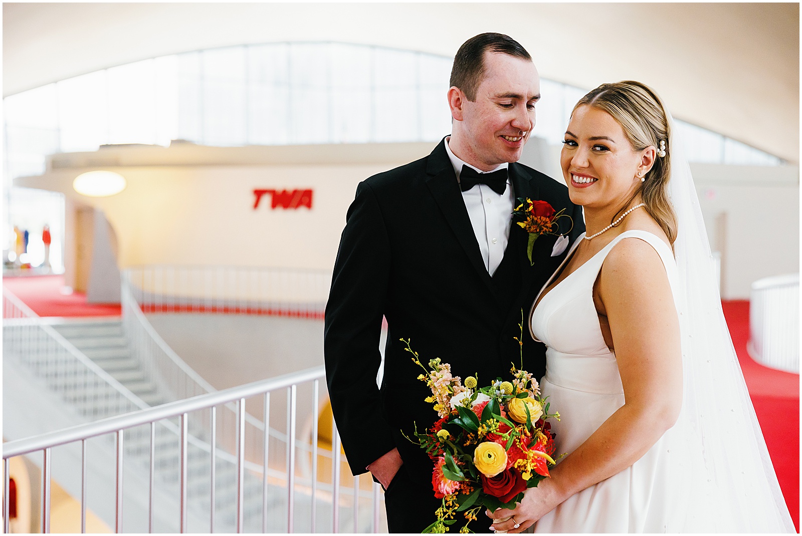 A couple having their TWA Hotel wedding captured in a lobby photo.