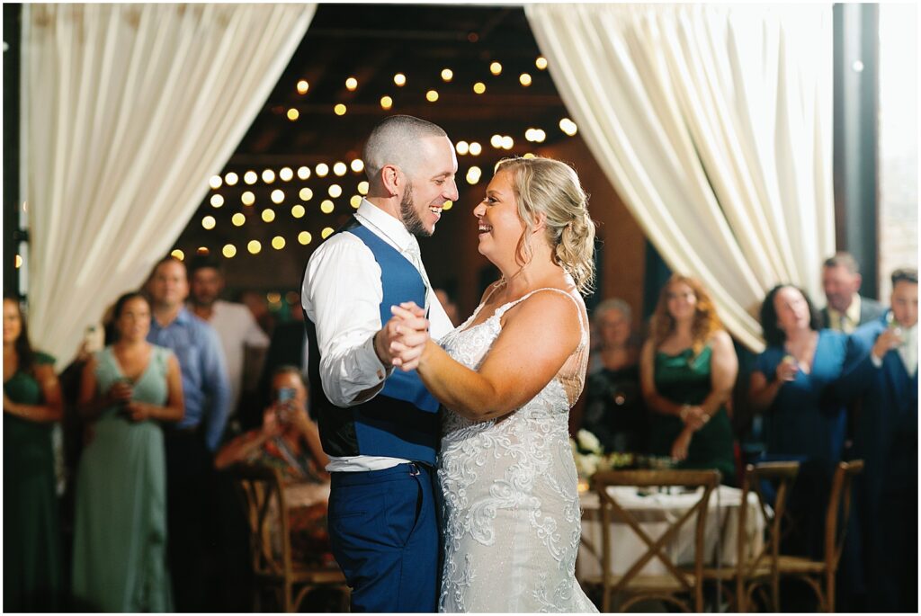 A bride and groom smile at each other during their first dance.