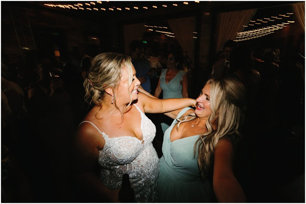 A bride and bridesmaid dance and sing along to a song.