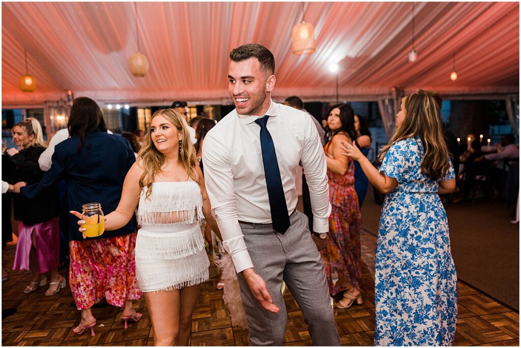 A bride in a fringe reception dress dances next to a groom.