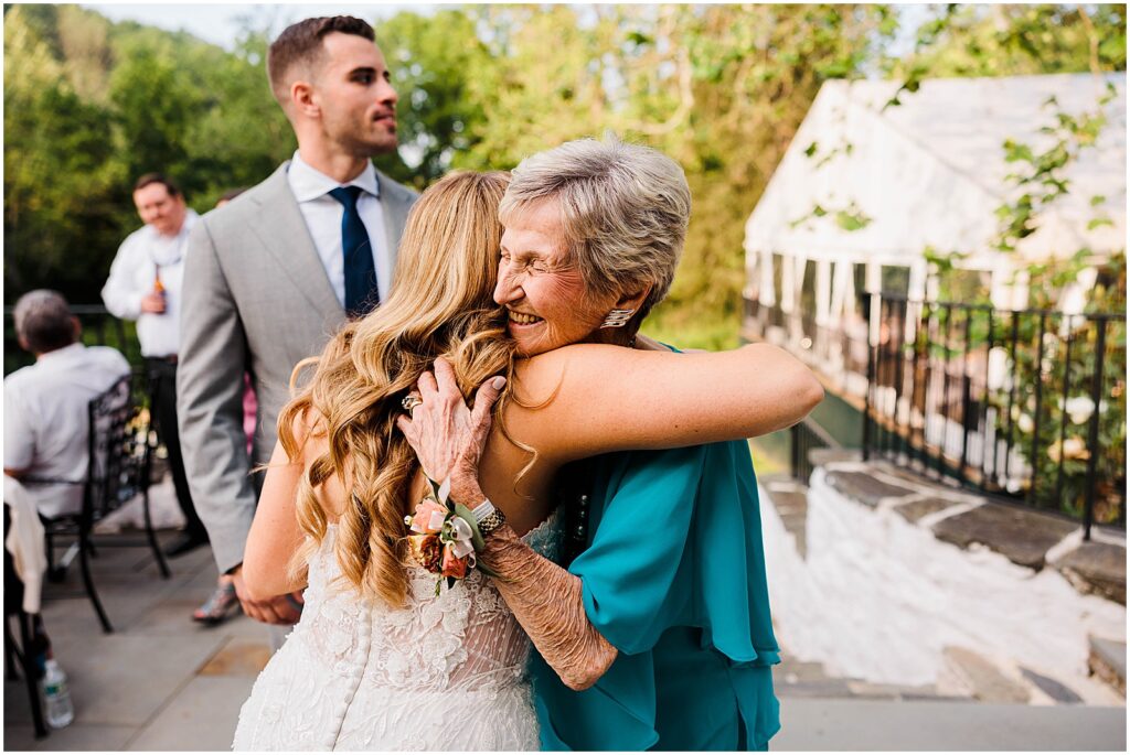 A bride embraces a family member during wedding cocktail hour.
