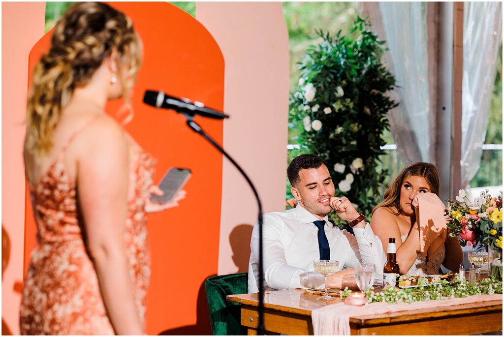 A bride wipes away a tear during a maid of honor speech.