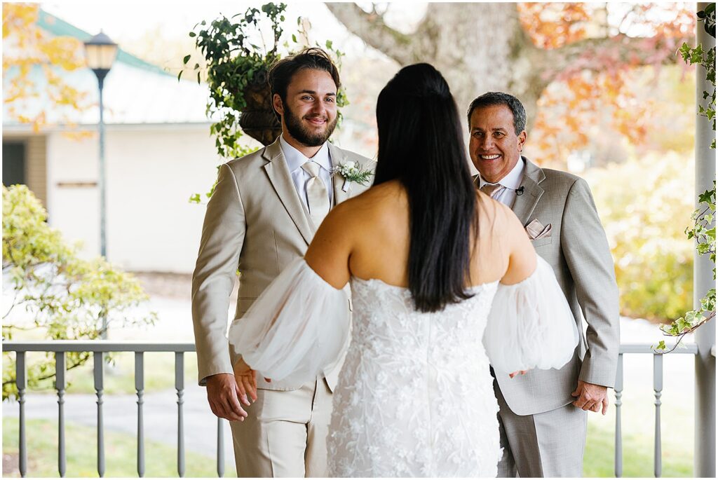 On a porch at Springton Manor Farm, a bride has a first look with her father and brother.