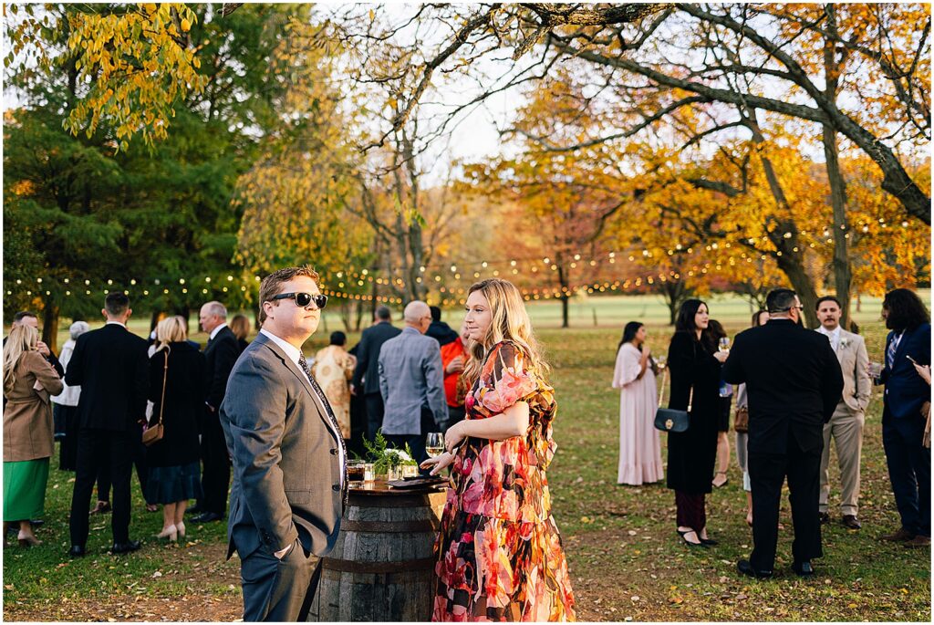 Wedding guests gather for cocktail hour at a fall wedding.