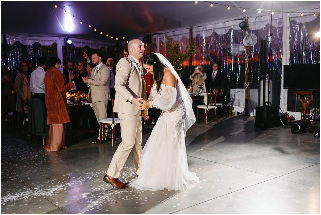 A groom leads a bride onto the dance floor for their first dance.
