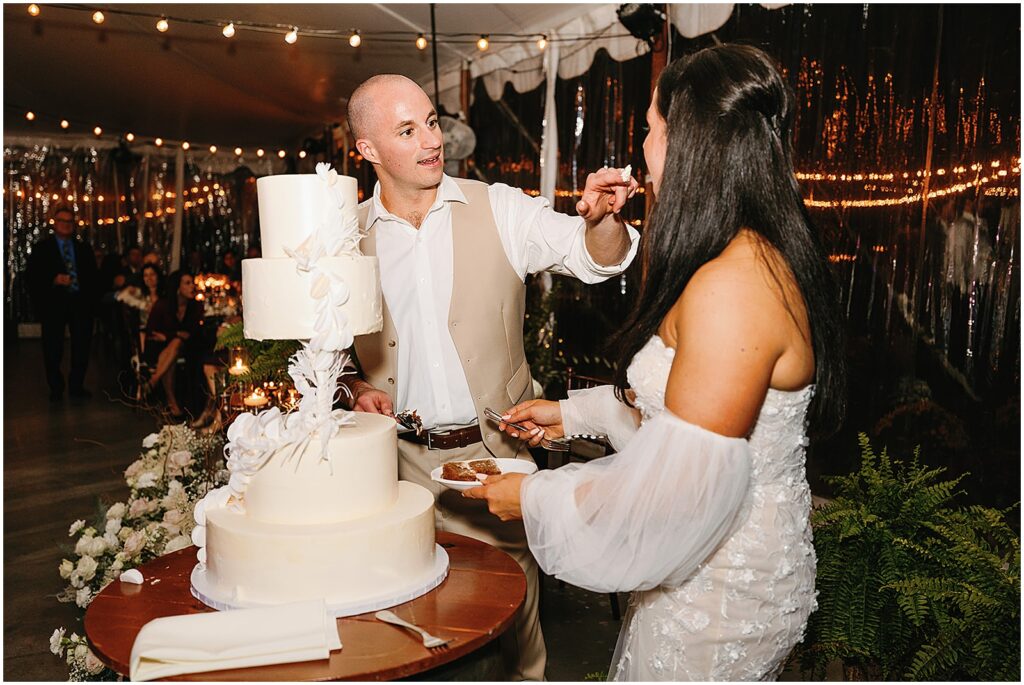 A bride and groom cut a tiered wedding cake.