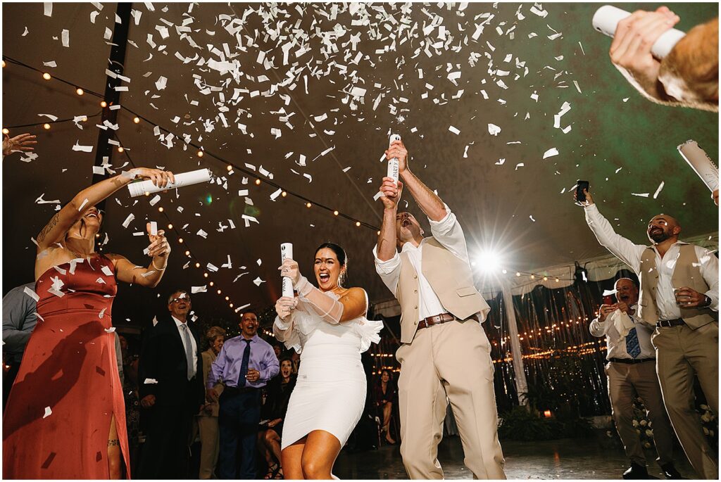 A bride and groom shoot off confetti cannons at their Springton Manor Farm wedding.