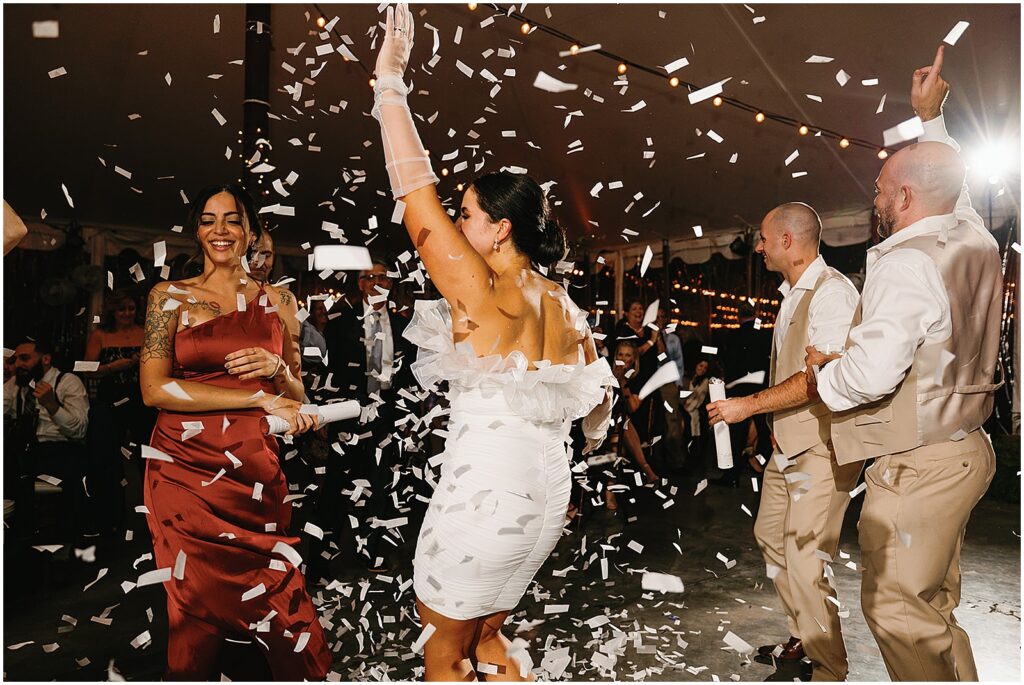 A bride in a reception dress dances in confetti.