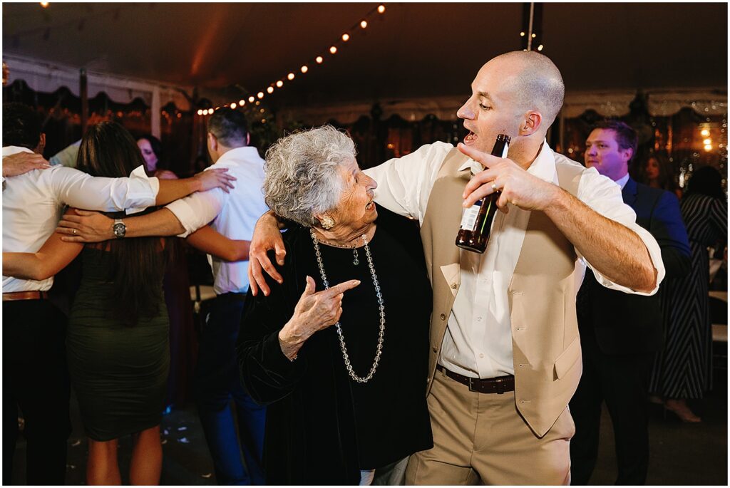 A groom dances with an elderly family member.