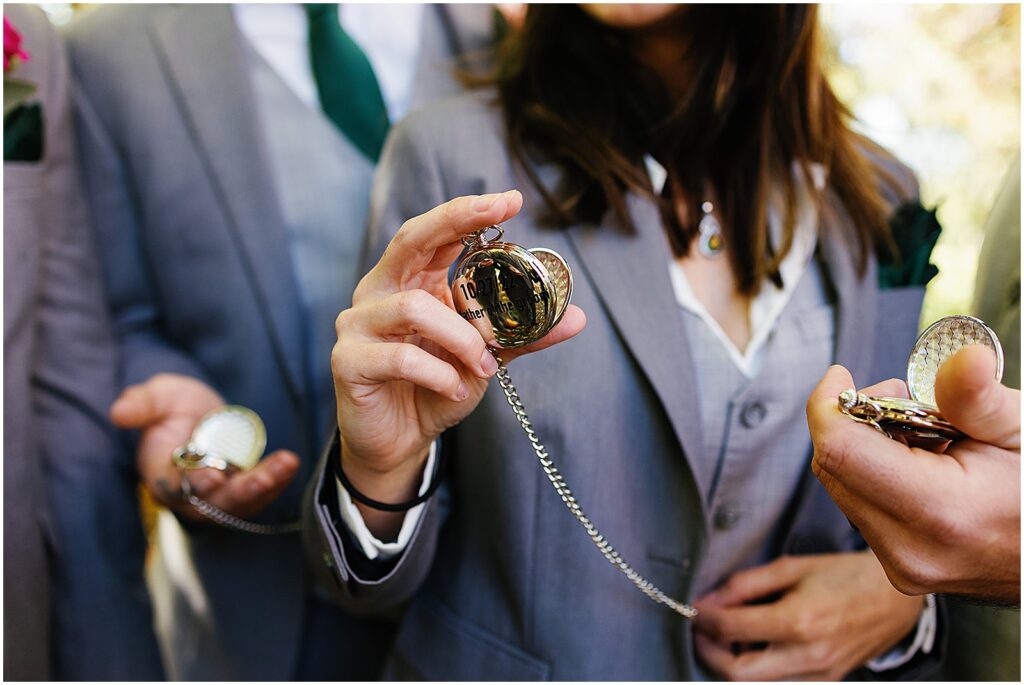A groom's wedding party holds out their pocket watches.