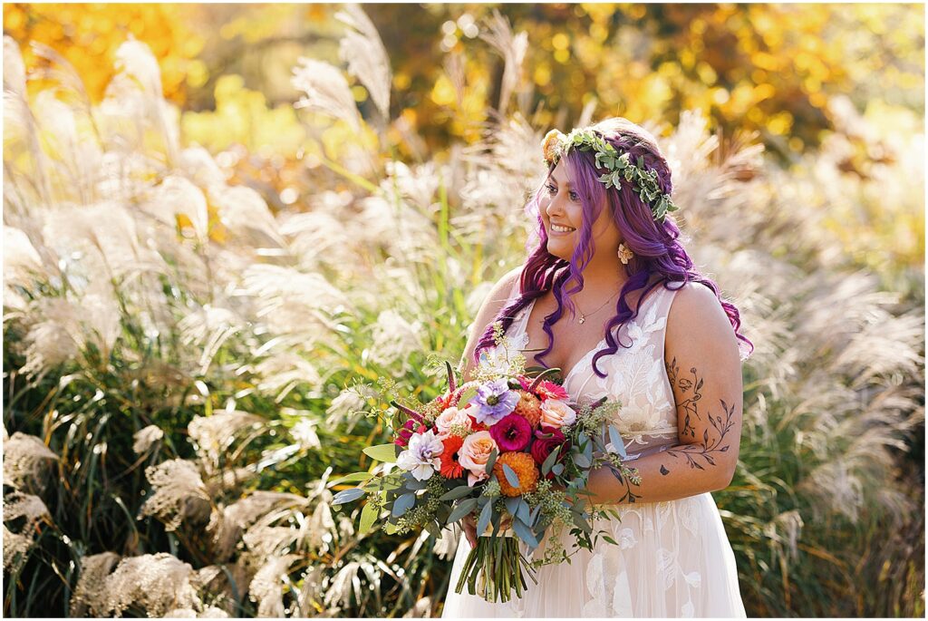 A bride with purple hair poses with a bridal bouquet at the Estate at Eagle Lake.