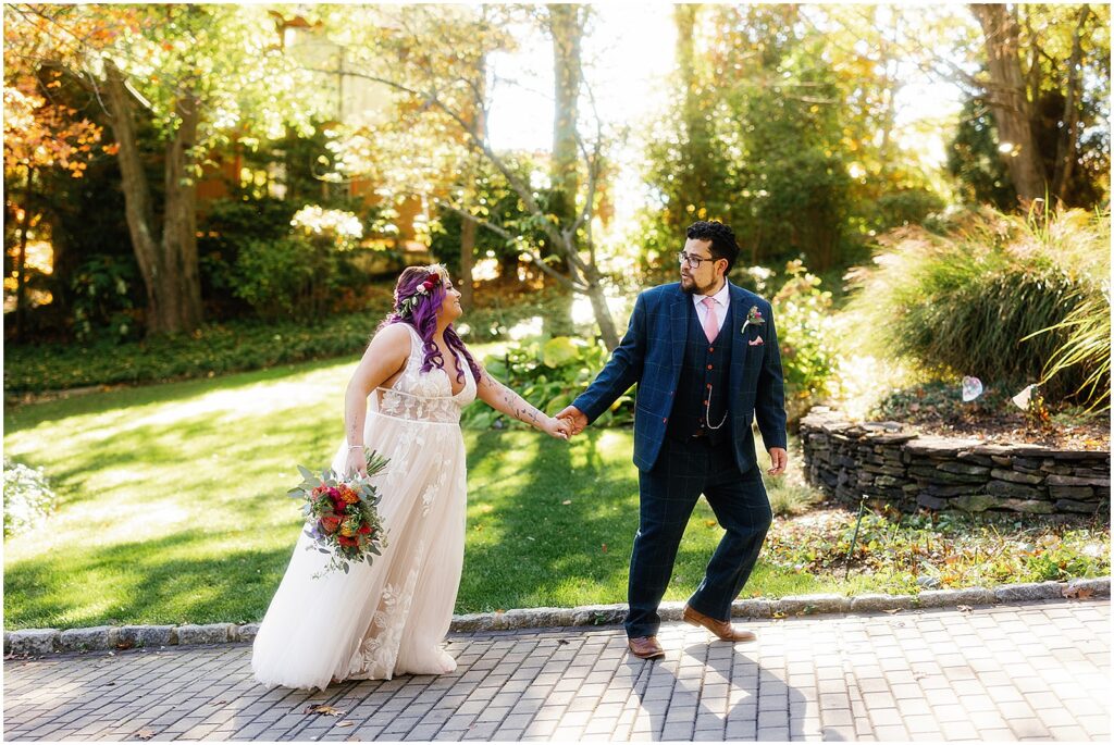 A groom leads a bride by the hand down a path before their wedding at the Estate at Eagle Lake.