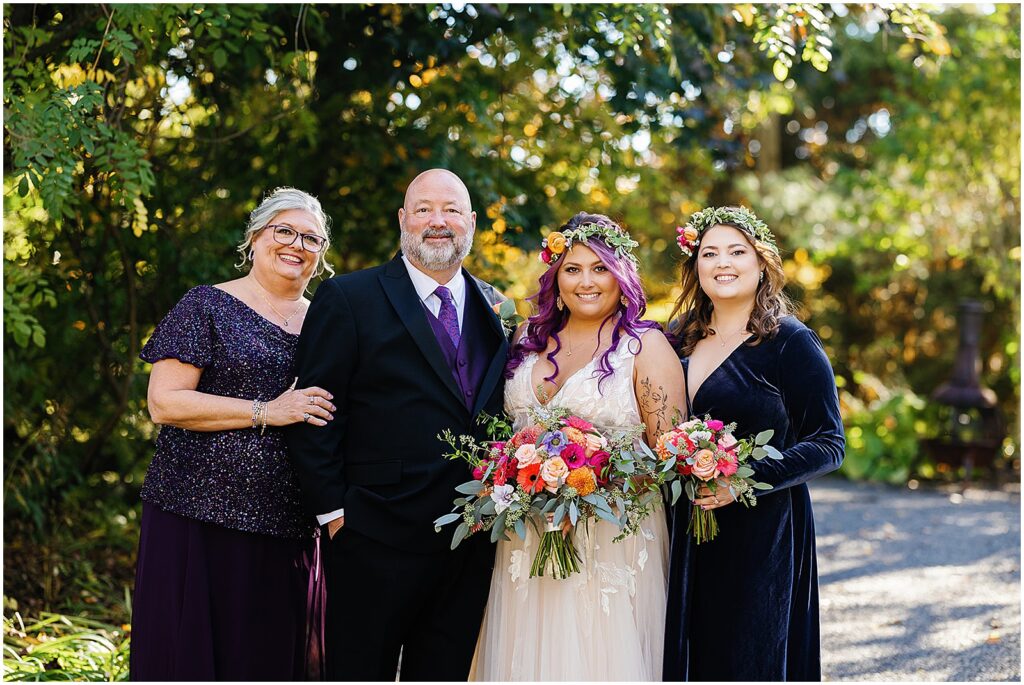 A bride poses with parents and a sister for formal family photos.