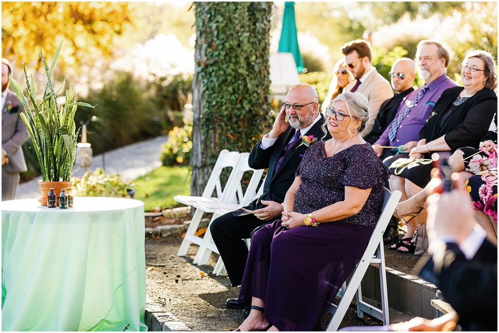 wedding guests watch a ceremony beside a table with a snake plant.