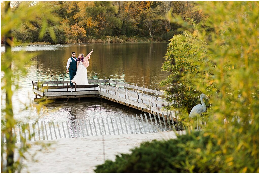 A bride and groom wave from the dock at the estate at eagle lake.