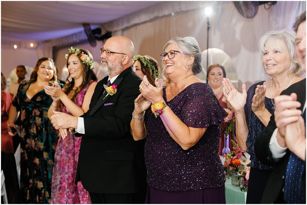 Wedding guests clap as a couple enters a wedding reception.