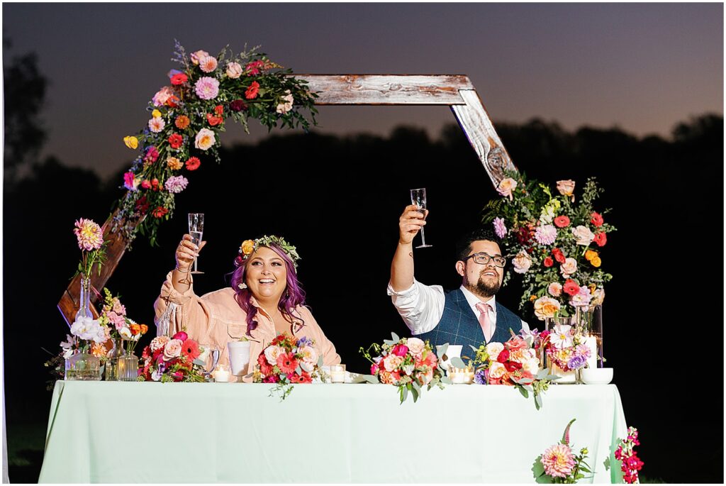 A bride and groom raise their glasses at the end of a speech at the estate at eagle lake.