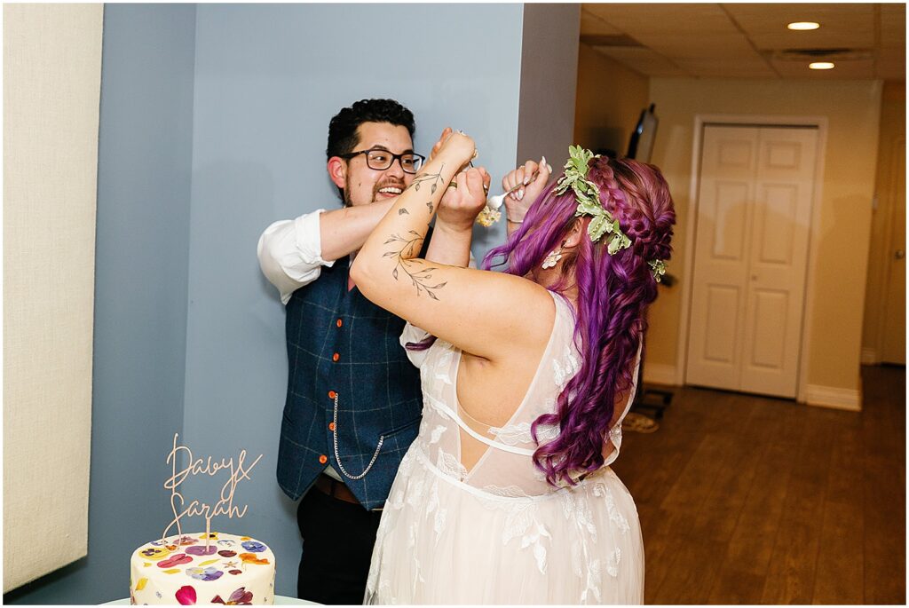 A bride and groom smash cake into each other's faces.