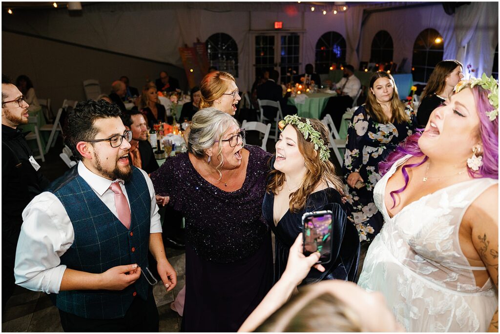 A groom and bride sing along to a song on a dance floor.