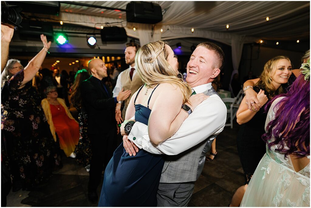 A woman jumps into a man's arms on the dance floor.