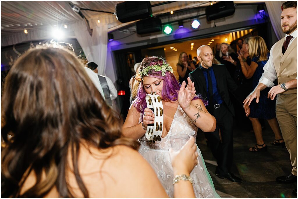 A bride plays with a tambourine at her wedding reception.