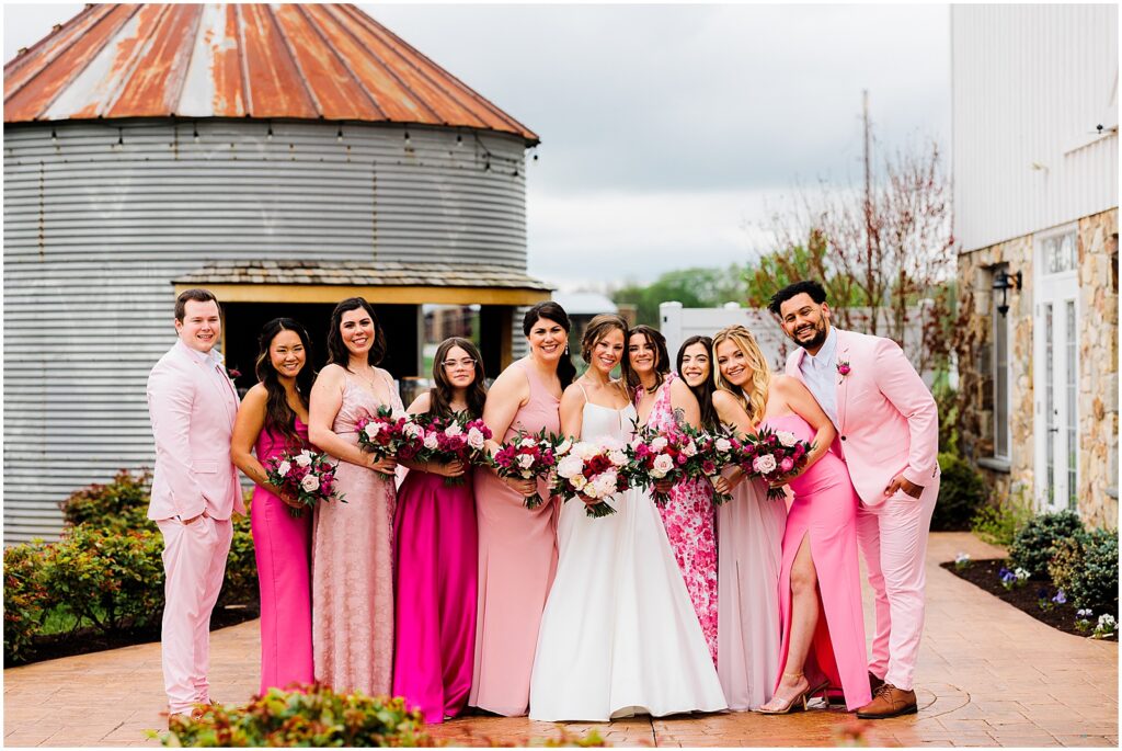 A bride poses with members of her wedding party dressed in pink at the Barn at Stoneybrooke.