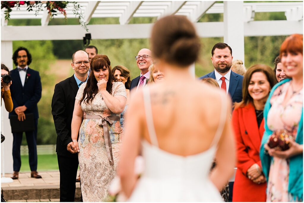 A bride's family members tear up as she walks down the aisle.