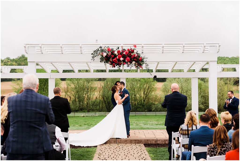 A bride and groom share their first kiss at the end of their spring wedding ceremony.