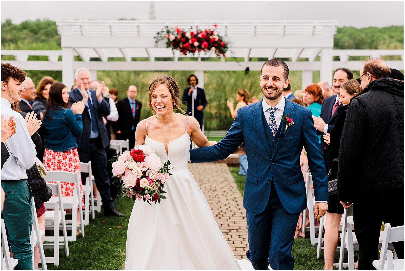 A bride and groom smile as they walk their recessional at the Barn at Stoneybrooke.