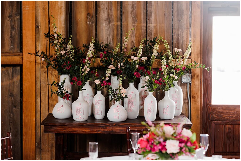 Vases are painted with a seating chart for a Barbiecore wedding.