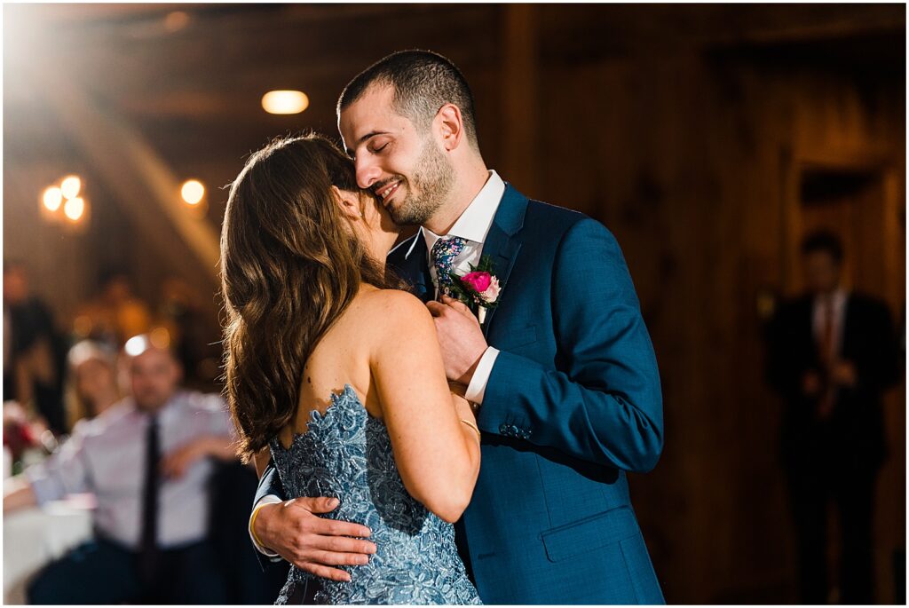 A groom presses his cheek to his mother's as they dance.