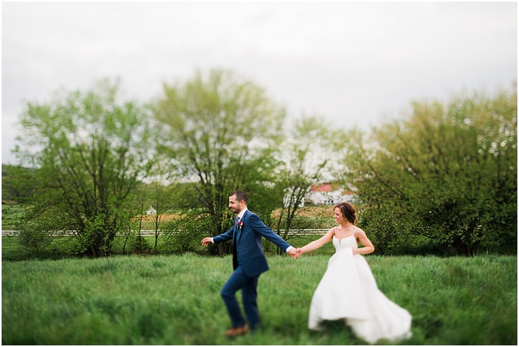 A bride and groom run through a field for wedding portraits at a Pennsylvania wedding venue.