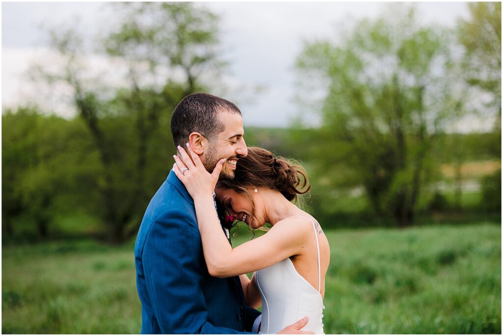 A bride leans on a groom laughing in a field at a Pennsylvania wedding venue.