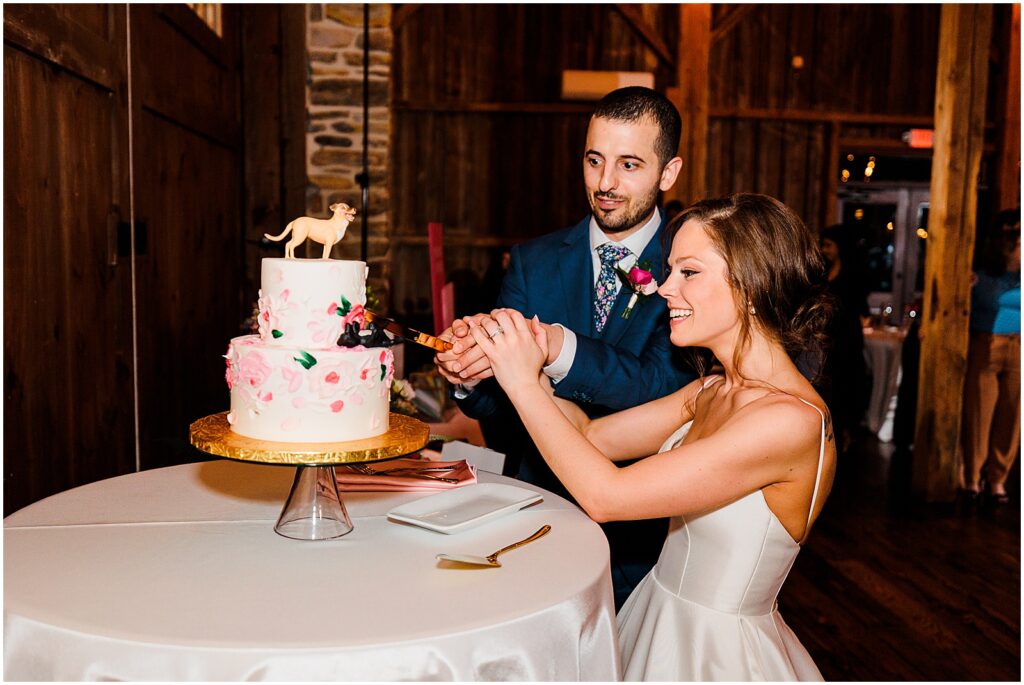 A bride and groom cut a wedding cake decorated with Barbiecore wedding decor.