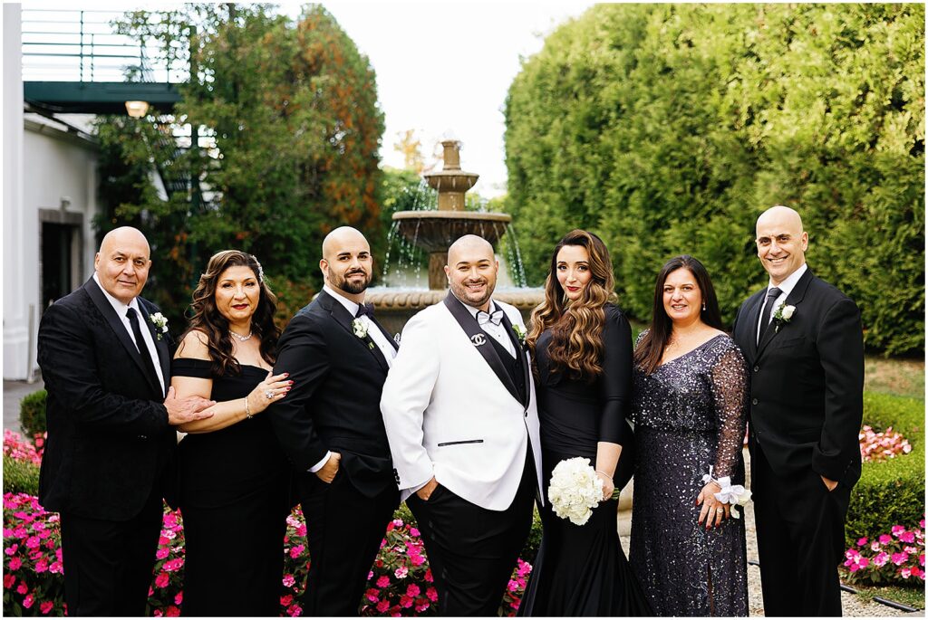 Two grooms pose with their families for formal portraits.