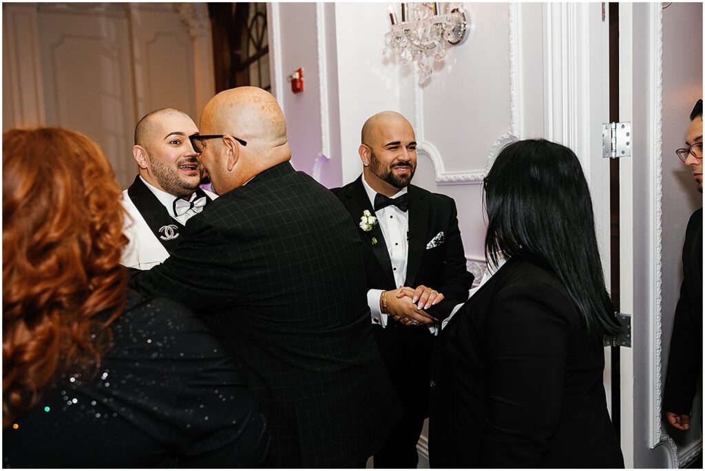 Grooms greet wedding guests entering a new Jersey wedding reception.