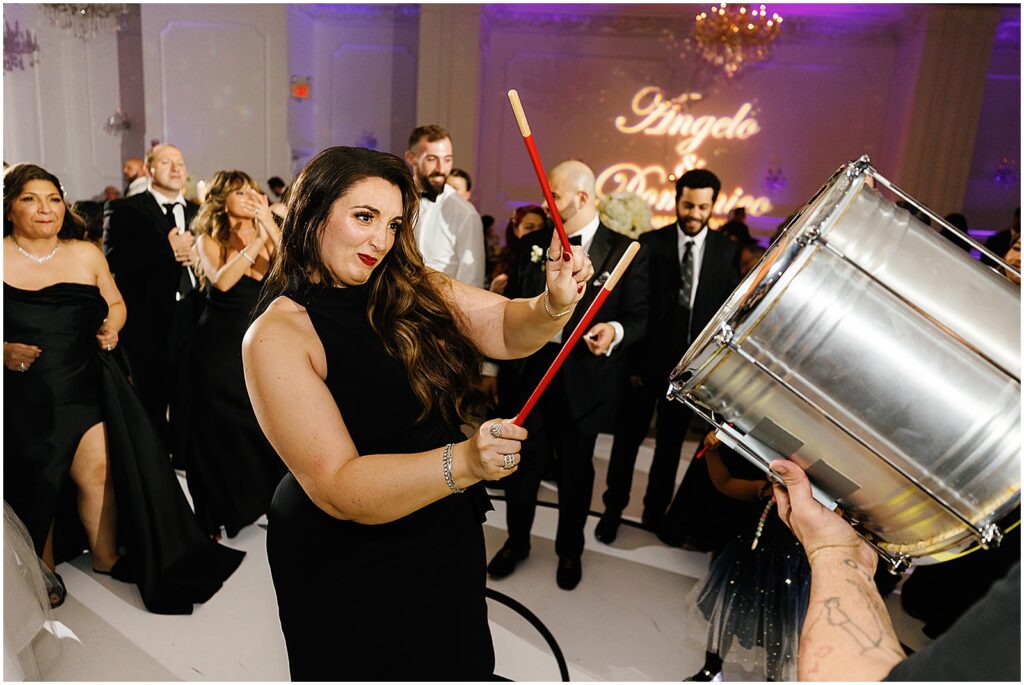 A woman beats a silver drum in a wedding reception.