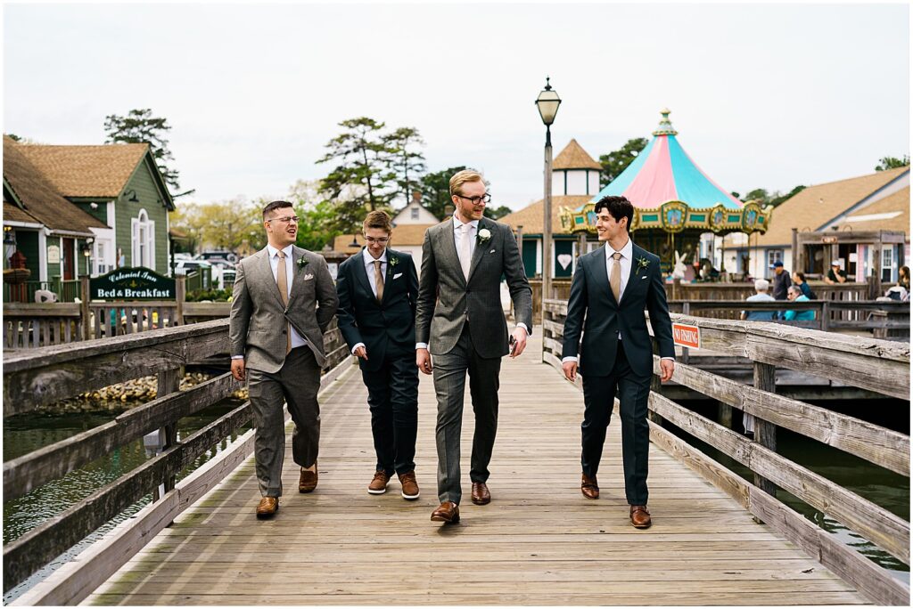 A groom walks with three groomsmen across a bridge towards a New Jersey wedding venue.