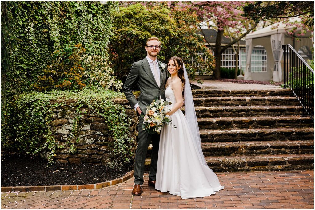 A bride and groom pose on a garden path outside a New Jersey wedding venue.