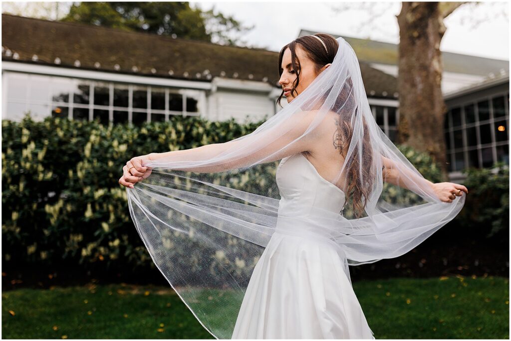 A bride spins and shows off her iridescent bridal veil in a garden.