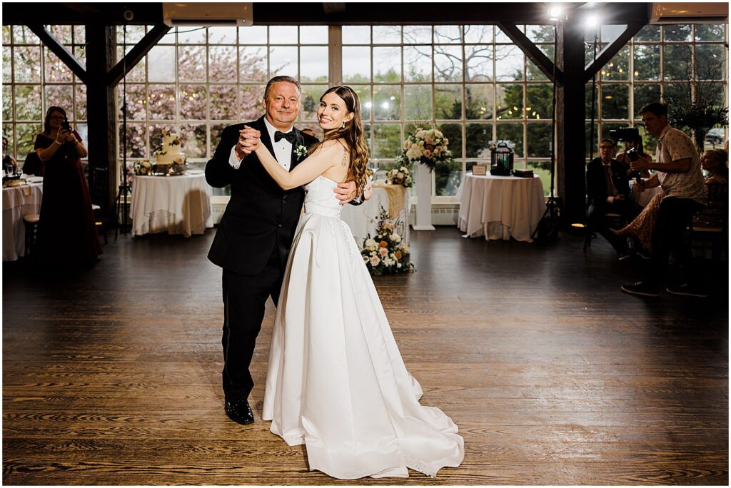 A bride and her father smile at a New Jersey wedding photographer during the father-daughter dance.