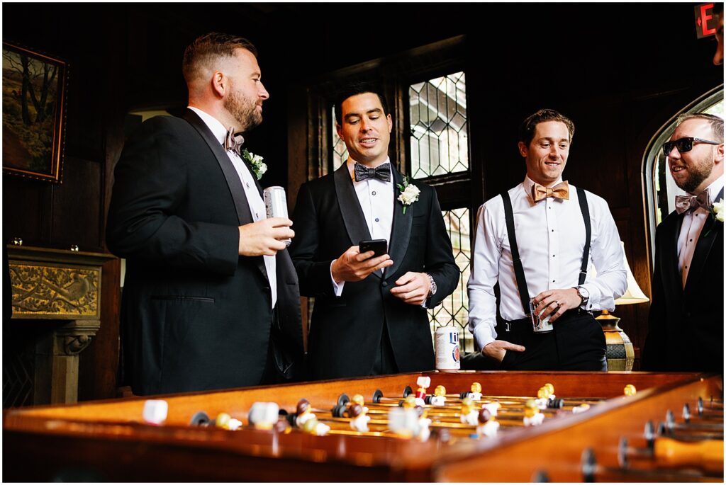 A groom stands around a table talking with groomsmen.