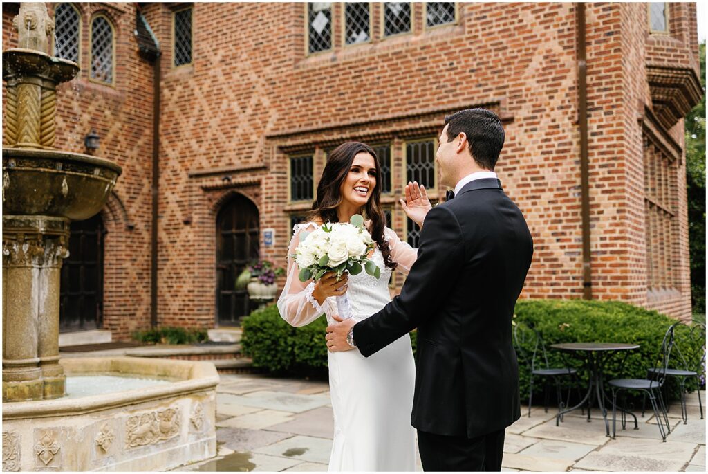 A bride and groom smile at each other in the courtyard of Aldie Mansion.