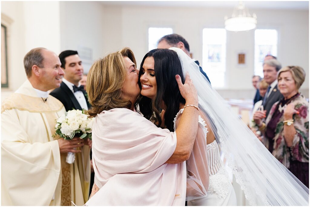 A family member kisses a bride on the cheek at a church wedding.
