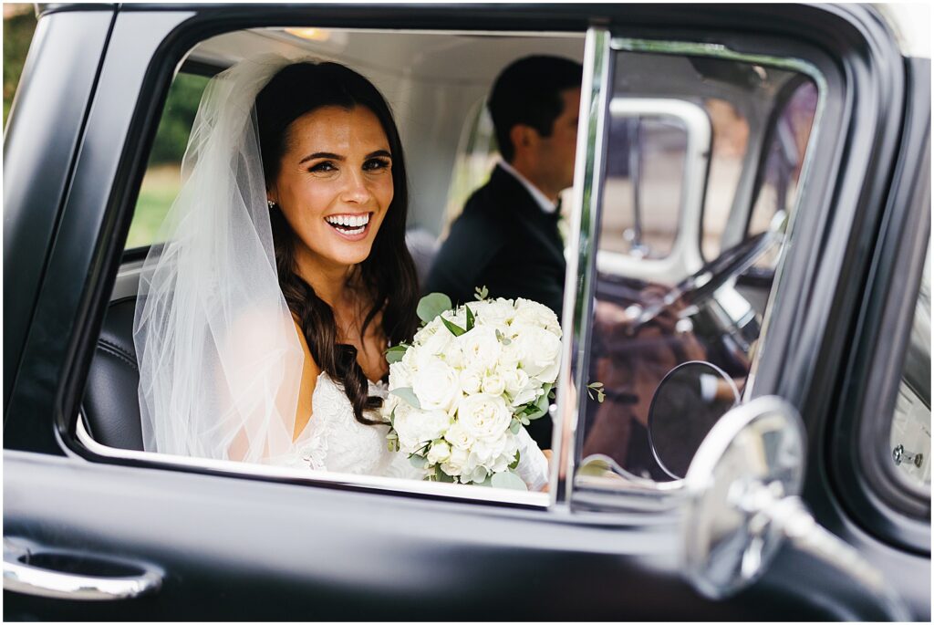 A bride and groom exit their wedding ceremony in a vintage car.