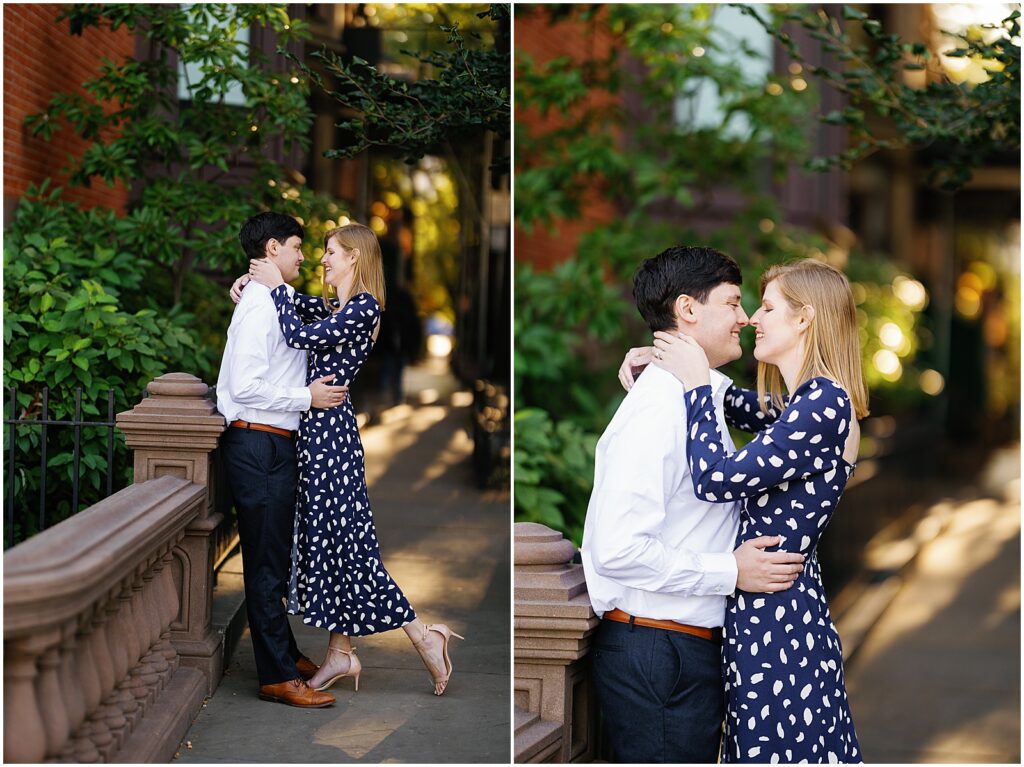 A man leans against a low stone wall and cuddles his fiancee in Brooklyn engagement photos.